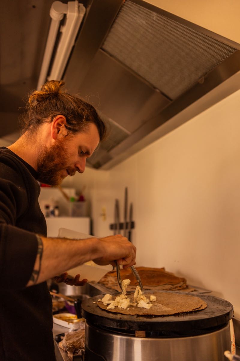 Kevin prépare une crêpe dans la caravane